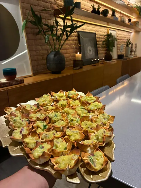 Finger food: cestinhas crocantes recheadas, em travessa dourada, num aparador com velas e plantas
