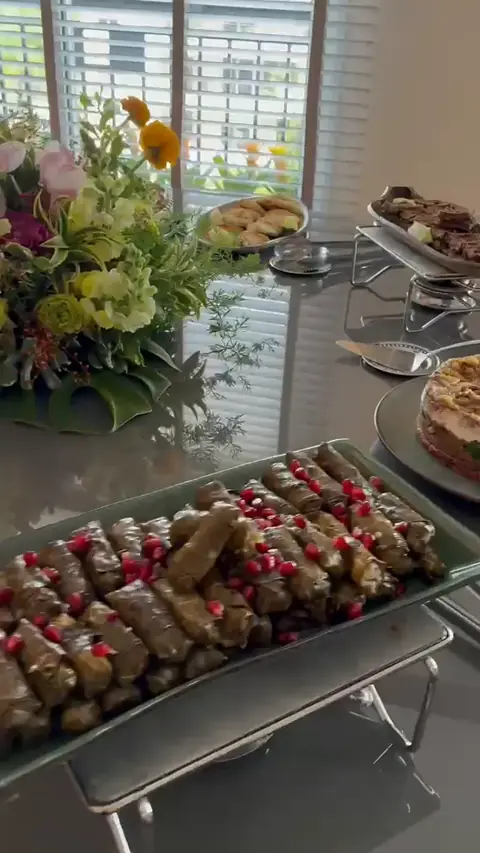 Travessa de charutinho com romã sobre réchaud, perto da janela, com arranjo de flores ao fundo
